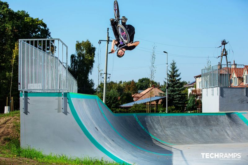 Rider na BMX wykonuje efektowny backflip nad quarter pipem w skateparku Zielonka