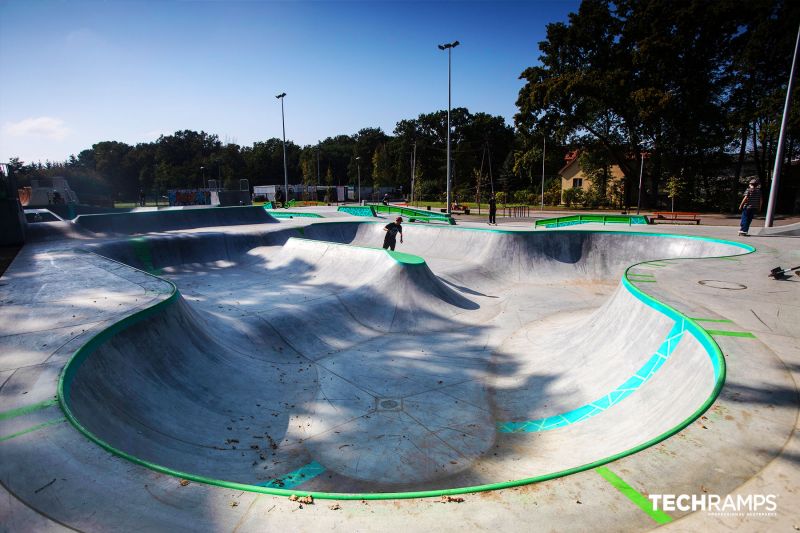 Szeroki widok na przestronny bowl z zielonymi krawędziami w skateparku Zielonk