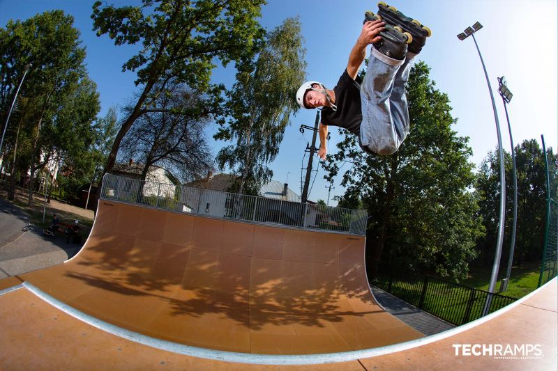 Rider na rolkach wykonuje trick na drewnianej rampie vert w skateparku Zielon